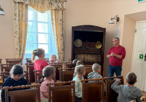 Dzieci słuchają wprowadzającej muzyki odtwarzanej na fisharmonii.