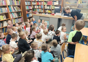 Dzieci z grup „Żabki”, „Misie” i „Stokrotki” słuchają jak pani bibliotekarka opowiada o pracy w bibliotece.