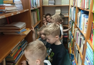 Dzieci oglądają książki, które znajdują się w szkolnej bibliotece.