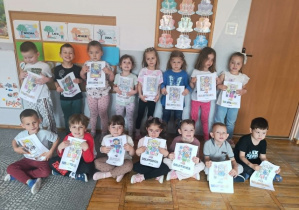 Dzieci z grupy „Stokrotki” dumnie prezentują swoją pracę plastyczną wykonaną z okazji Dnia Bibliotekarza.