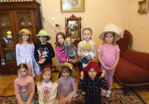 Zdjęcie przedstawia dziewczynki w kapeluszach z dawnych czasów w jednym z pomieszczeń.