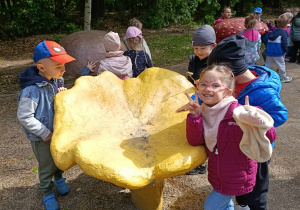Dzieci pozują do zdjęcia z ogromnym grzybem - kurką
