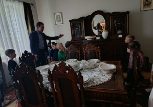 Dzieci oglądają zastawę stołową oraz meble z dawnych czasów.