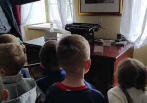 Dzieci oglądają dawną maszynę do pisania będącą na wyposażeniu muzeum.