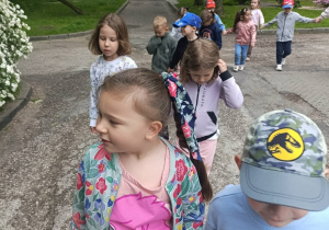 Dzieci w parach jedna za drugą spacerują w pobliżu przedszkola.