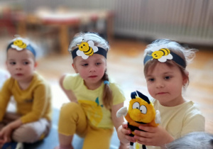 Dziewczynka prezentuje maskotkę pszczoły.