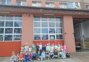 Na zdjęciu widzimy grupę dzieci ze Smerfów i Motylków przed remizą strażacką