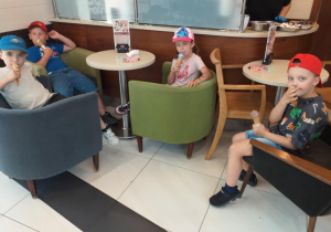 Zdjęcie przedstawia dzieci jedzące lody w pobliskiej lodziarni.
