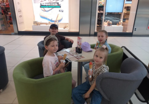 Zdjęcie przedstawia dzieci jedzące lody w pobliskiej lodziarni.