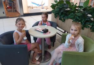 Zdjęcie przedstawia dzieci jedzące lody w pobliskiej lodziarni.