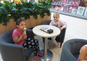 Zdjęcie przedstawia dzieci jedzące lody w pobliskiej lodziarni.