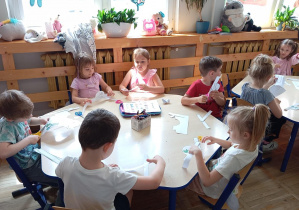 Na zdjęciu dzieci z grupy Odkrywcy wykonują kolorowe opaski na głowę.
