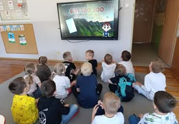 Dzieci z grupy Misie oglądają film edukacyjny o bezpiecznych wakacjach w górach i nad morzem.
