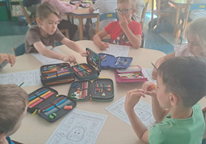 Przedszkolaki z grupy Misie wykonują zadania ucząc się co należy zabrać na wycieczkę w góry.