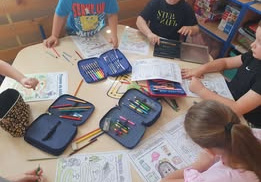 Dzieci z grupy Smerfy kolorują pracę na temat bezpiecznych wakacji w górach i nad morzem.