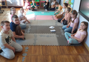Zdjęcie przedstawia dzieci po ułożeniu kamieni z papieru według poleceń nauczyciela.