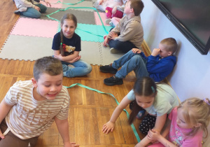 Zdjęcie przedstawia dzieci prezentujące swoje figury geometryczne ułożone wspólnie w grupach.