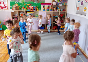 Dzieci chodzą w kole i grają na samodzielni wykonanych grzechotkach.