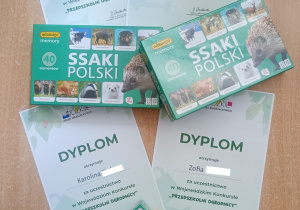 Zdjęcie prezentujące dyplomy oraz upominki dla dzieci za udział w konkursie.