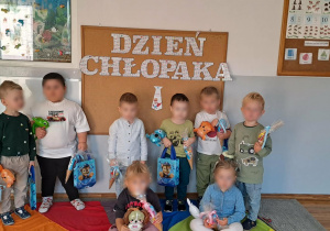 Dzieci pozują do grupowego zdjęcia z upominkami.