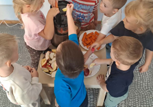 Dzieci z grupy Stokrotki przygotowują sok z jabłek i marchewki.