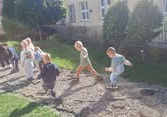 Dzieci z grupy Stokrotki kroczą razem po ścieżce sensorycznej, ucząc się współpracy, wzajemnego wsparcia i budowania pierwszych więzi poprzez wspólną zabawę na świeżym powietrzu.