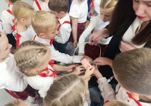 Dzieci z grupy „Żabki” sięgają po własnoręcznie wykonane upominki, aby wręczyć je pracownikom przedszkola.