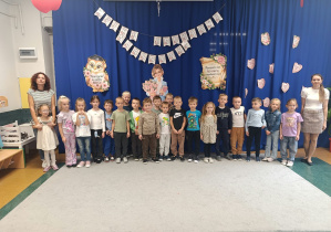 Grupa „Motylki” pozuje do zdjęcia na tle dekoracji wykonanej z okazji Dnia Edukacji Narodowej.