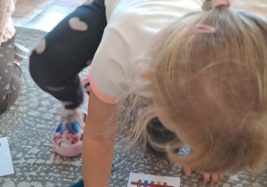 Dziewczynka odwzorowuje wzór, układając kolorowe patyczki.