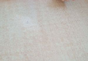 Dziewczynka dmucha na piórko podczas zabawy oddechowej.