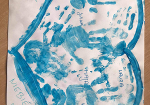 Plakat wykonany przez grupę Żabki. Na białym kartonie namalowany niebieską farbą kontur serca, wypełniony odbitymi na niebiesko dłońmi dzieci oraz podpisami dzieci. Po prawej i lewej na dole serca napis: „Jesteśmy z Wami Niebieskimi Motylami.