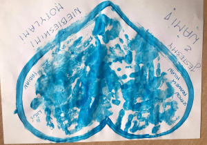 Na białym kartonie namalowany niebieską farbą kontur serca, wypełniony odbitymi na niebiesko dłońmi dzieci oraz podpisami kolejnych dzieci z grupy. Po prawej i lewej na dole serca napis: „Jesteśmy z Wami Niebieskimi Motylami”.