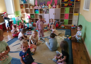 Dzieci bawią sie róznymi zabawkami na dywanie.