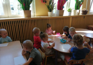 Dzieci siedzą przy stolikach i tworza swoje pierwsze prace plastyczne.