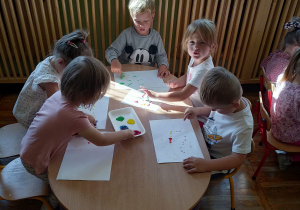 Dzieci maluja farbami za pomoca paluszków.