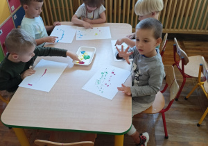 Pięcioro dzieci maluje farbami.