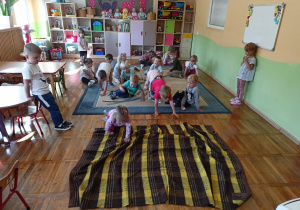 Dzieci uczestnicza w zabawie ruchowej z kocykiem.
