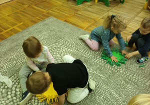 Dzieci na dywanie doskonalą umiejętności klasyfikacji pod względem koloru. Przyczepiają kolorowe spinacze do okręgów w danym kolorze.