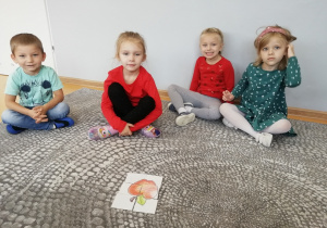 Dzieci siedzą wokół puzzli przedstawiających jabłko.
