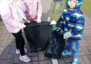 Dzieci z grupy Liski z pozbieranymi własnoręcznie śmieciami w czarnych workach.