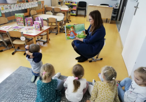 Nauczycielka pokazuje dzieciom ilustracją z książki.