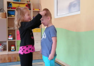 Dziewczynka zakłada chłopcu medal na szyję.