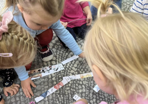 Dzieci układają na dywanie puzzle związane z Psim Patrolem.