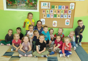 Dzieci wraz z gościem pod tablicą pozują do pamiątkowego zdjęcia.