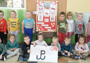 Stokrotki – na zdjęciu dzieci na tle tablicy z symbolami narodowymi Polski