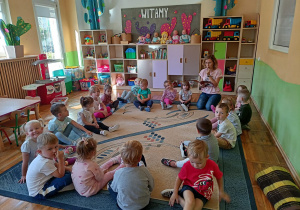 Dzieci z grupy Biedronki siedzą na dywanie i słuchają opowiadania „Mały Powstaniec”