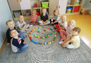 Przedszkolaki siedzą do około uśmiechniętej buzi ułożonej z klocków.