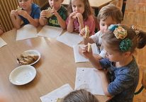 Przedszkolaki jedzą upieczony chlebek.