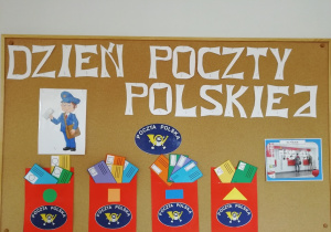 Tablica z napisem Dzień Poczty Polskiej oraz z czerwonymi papierowymi skrzynkami na listy.