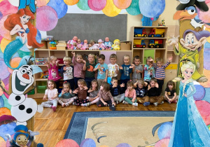 Zdjęcie grupowe przedstawiające usmiechnięte dzieci ustawione w dwóch rzedach. dookoła nich umieszczona kolorowa ramka przedstawiająca postaci z filmów rysunkowych.